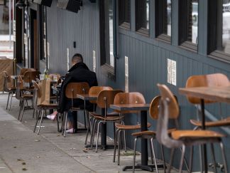 A person sits at a table outside of a restaurant in San Francisco, on Aug. 5.