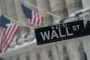 A Wall Street street sign outside the New York Stock Exchange as snow falls in New York, on Monday, Feb. 1, 2021.