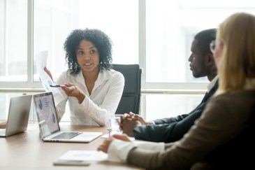 A woman explains a graph to two colleagues.