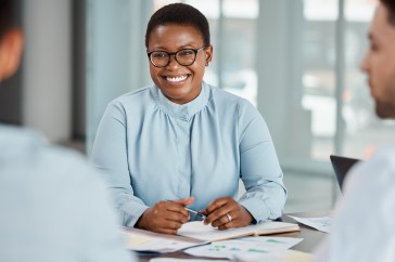 A Black woman smiling at her colleagues.