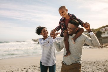 A Black family walks along the beach.
