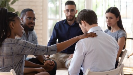 A support group of five comforts a fellow member.