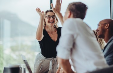 Two employees high-fiving each other at work
