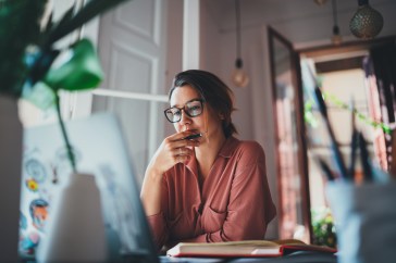 A young woman sits in front of laptop in her apartment.