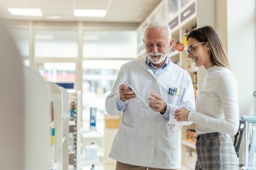 A pharmacist helps a customer in a sunlit store.