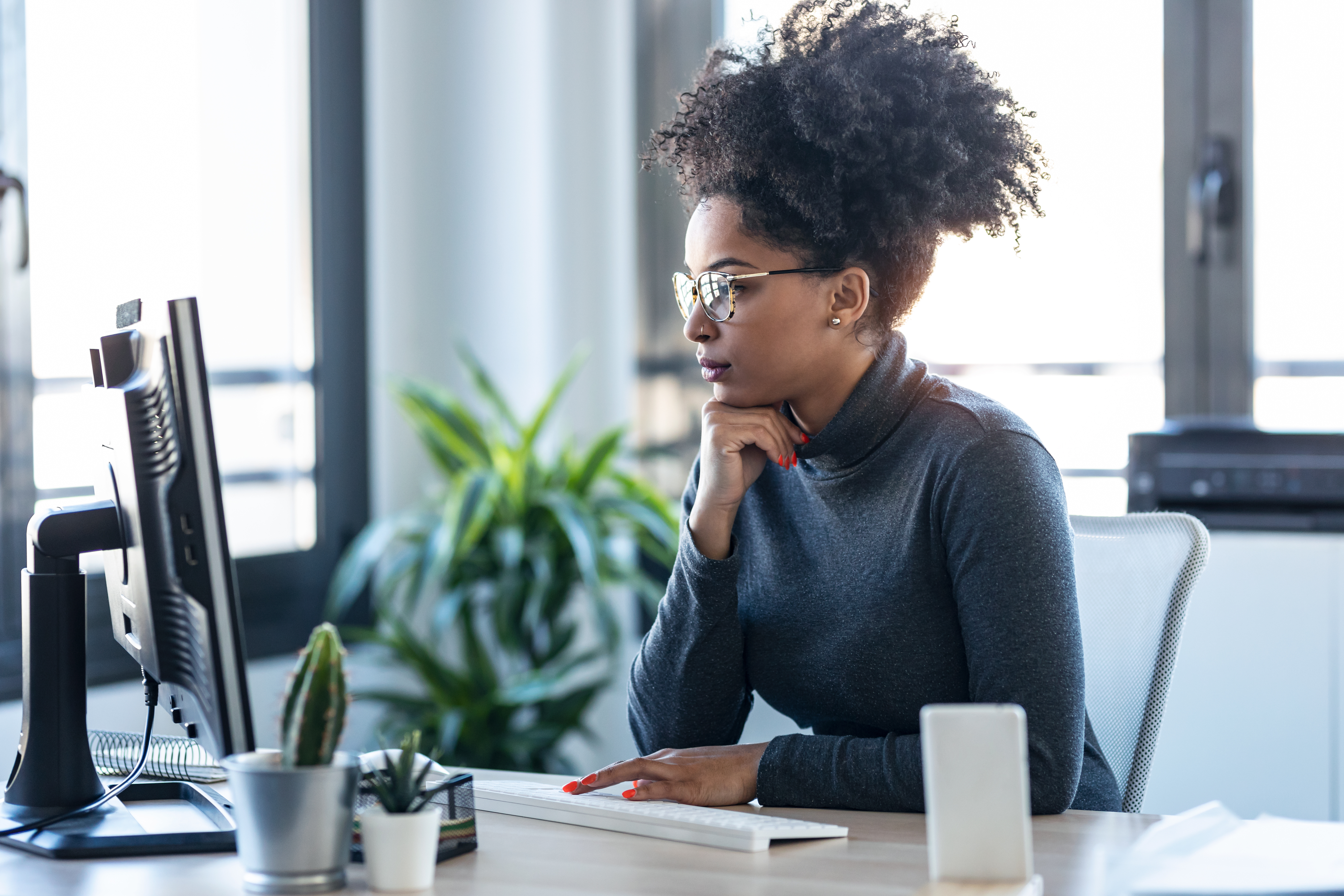 A woman at her desk, focused on her desktop.