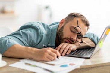 A man is asleep on his laptop.