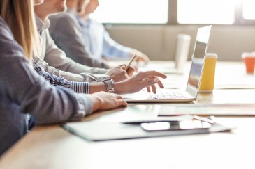 Workers at a conference table with laptops.
