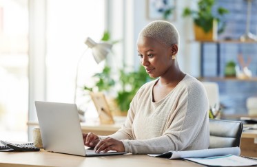 A young Black woman on her laptop.