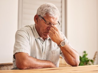 An elderly man is frustrated at the table.