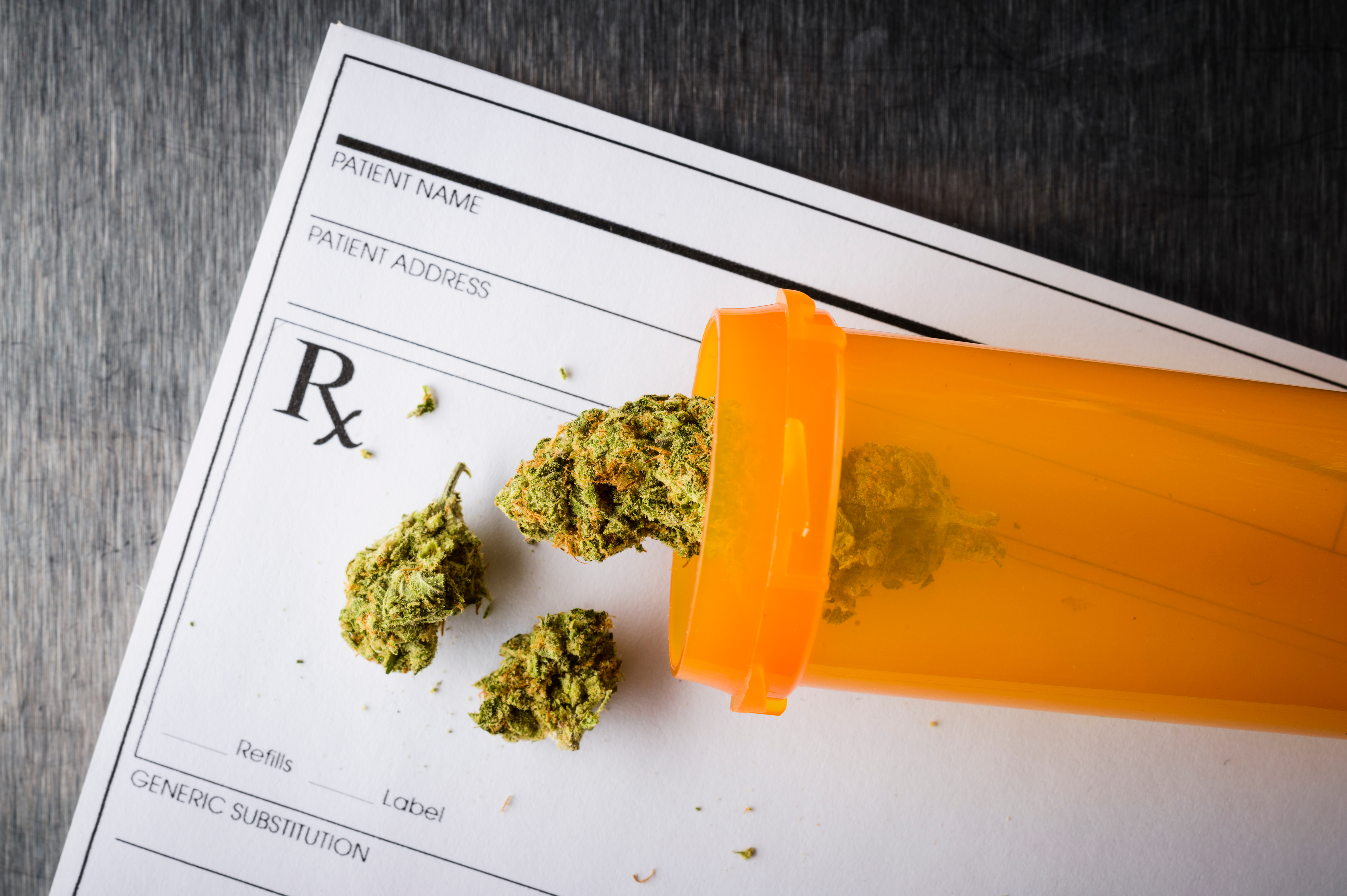 Marijuana buds spilling from a prescription medicine bottle.