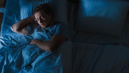 A young man is asleep in his bed.