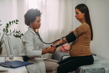 A doctor takes the blood pressure of a pregnant woman.