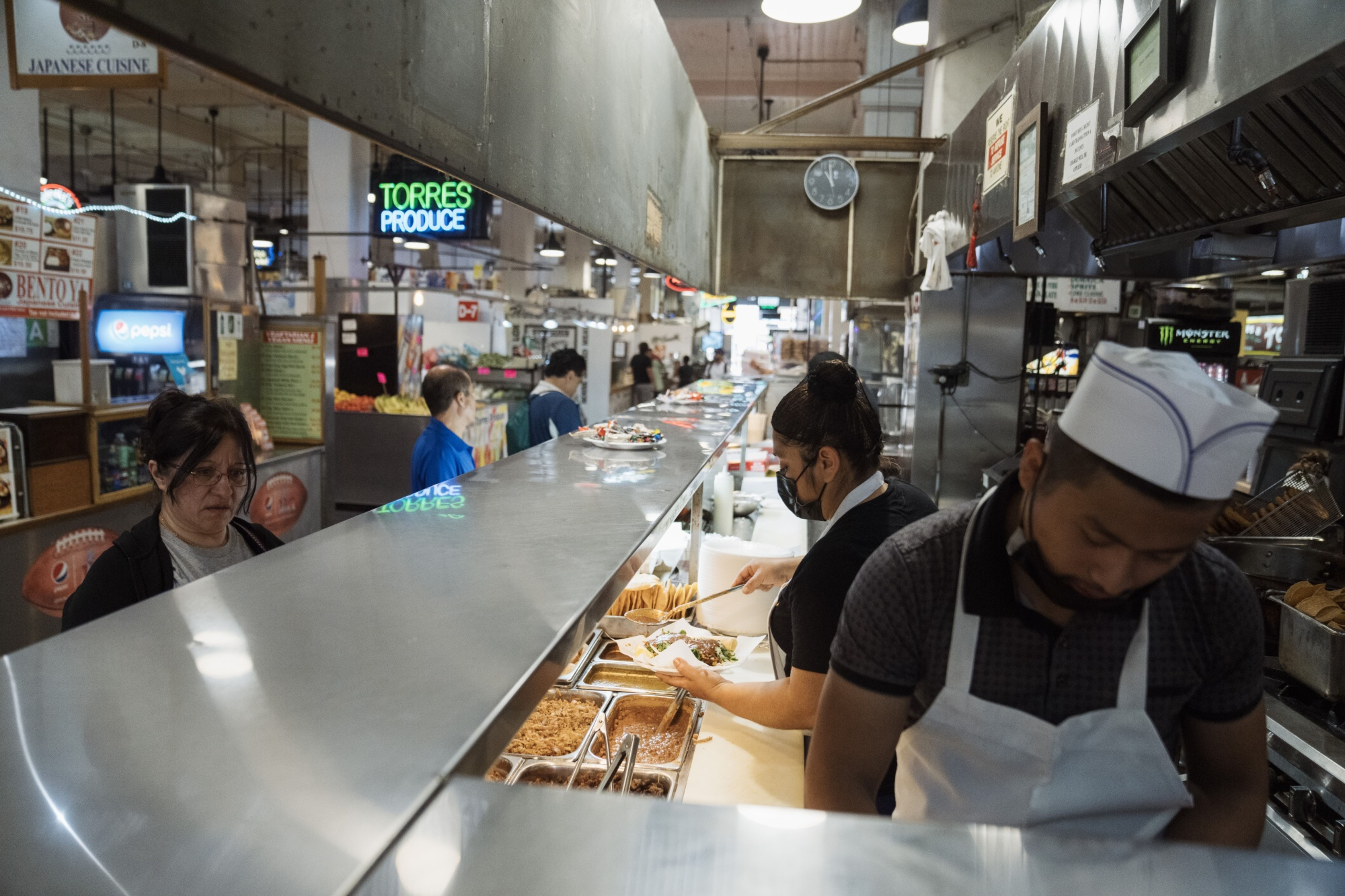 Workers serve customers food in a cafeteria.