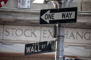 Wall Street sign in the foreground, with the stock exchange building in the background.
