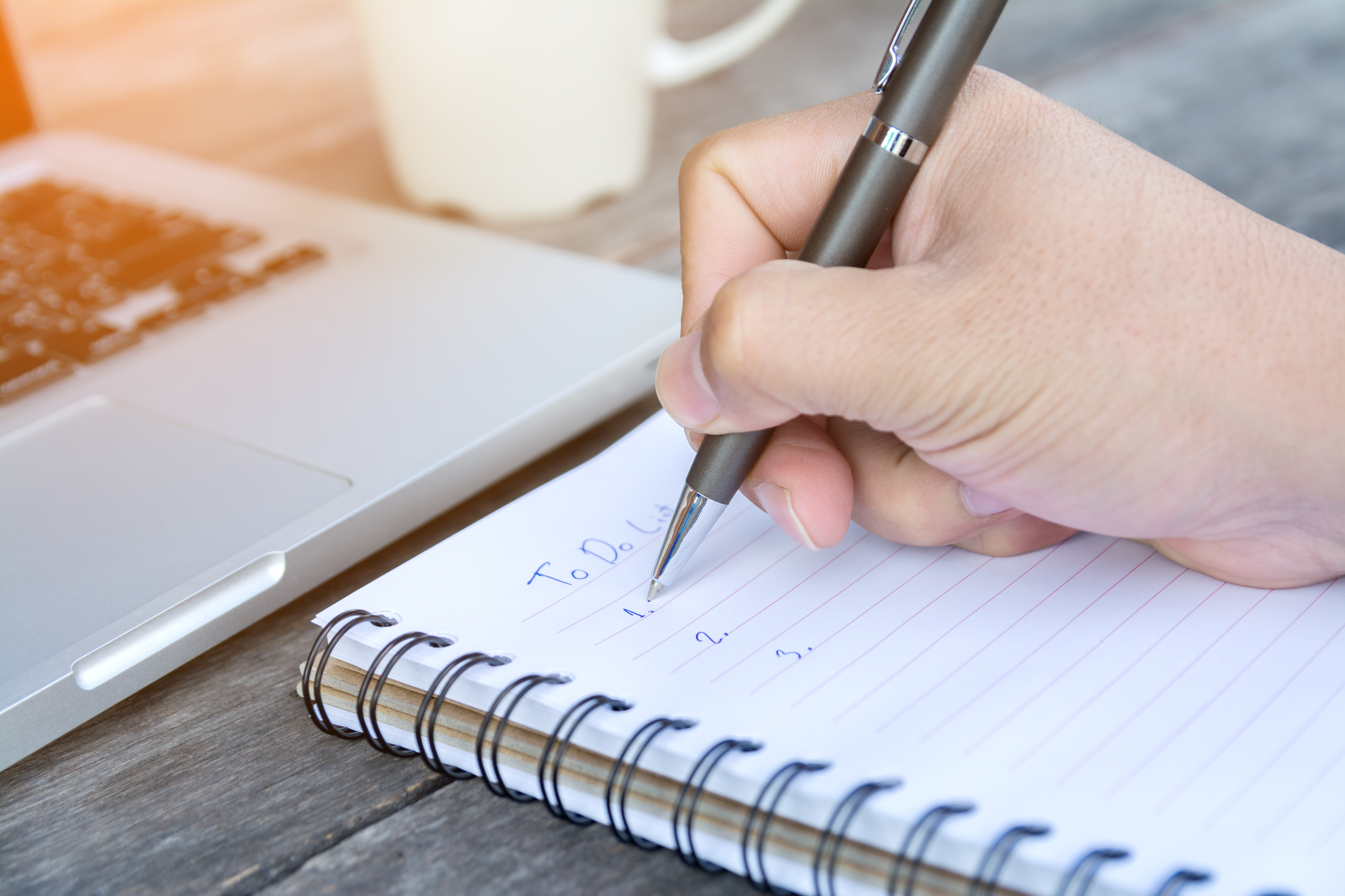 Person writing out their to do list in a notebook