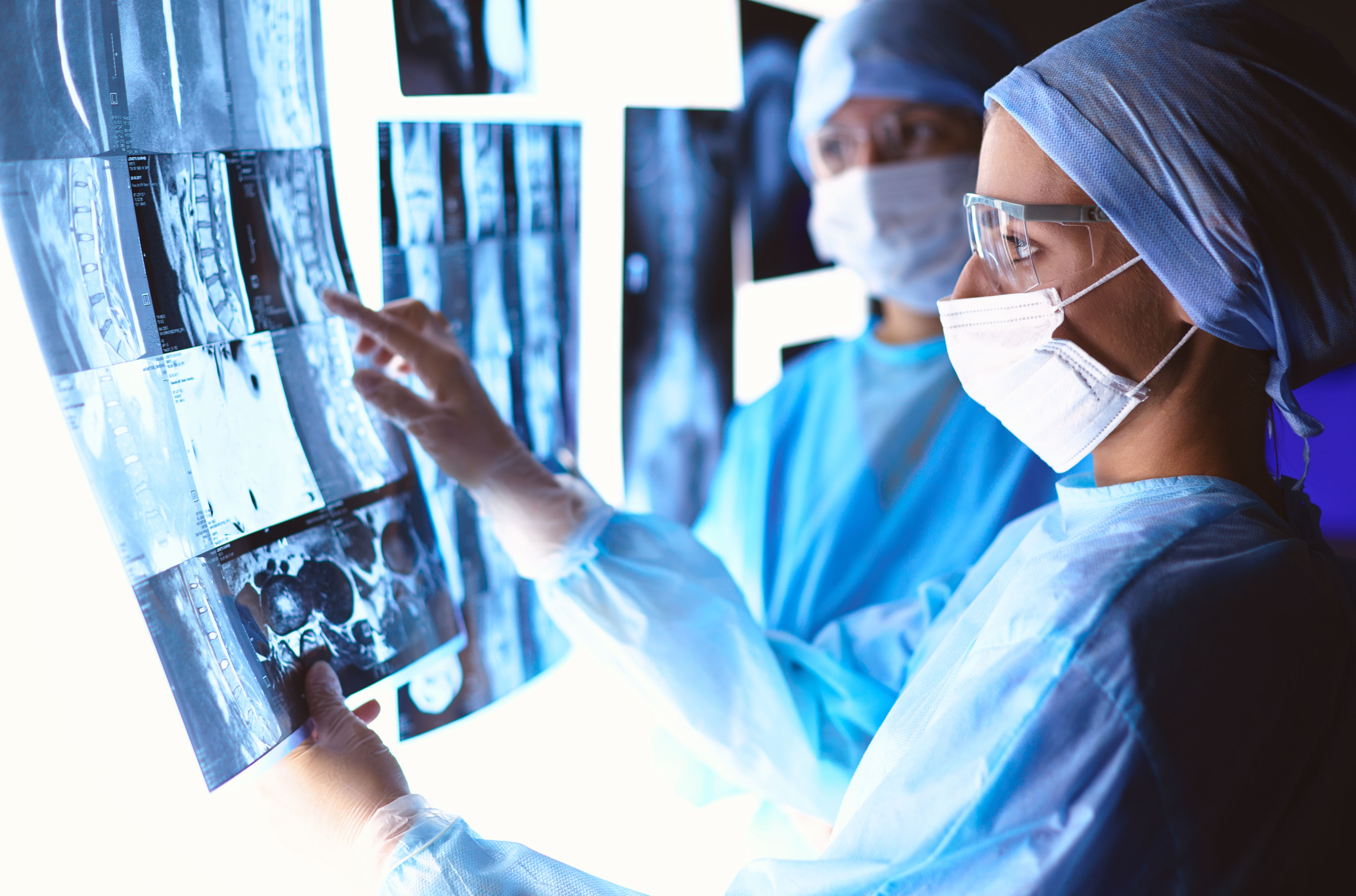 Two doctors analyzing X-rays under bright white light.