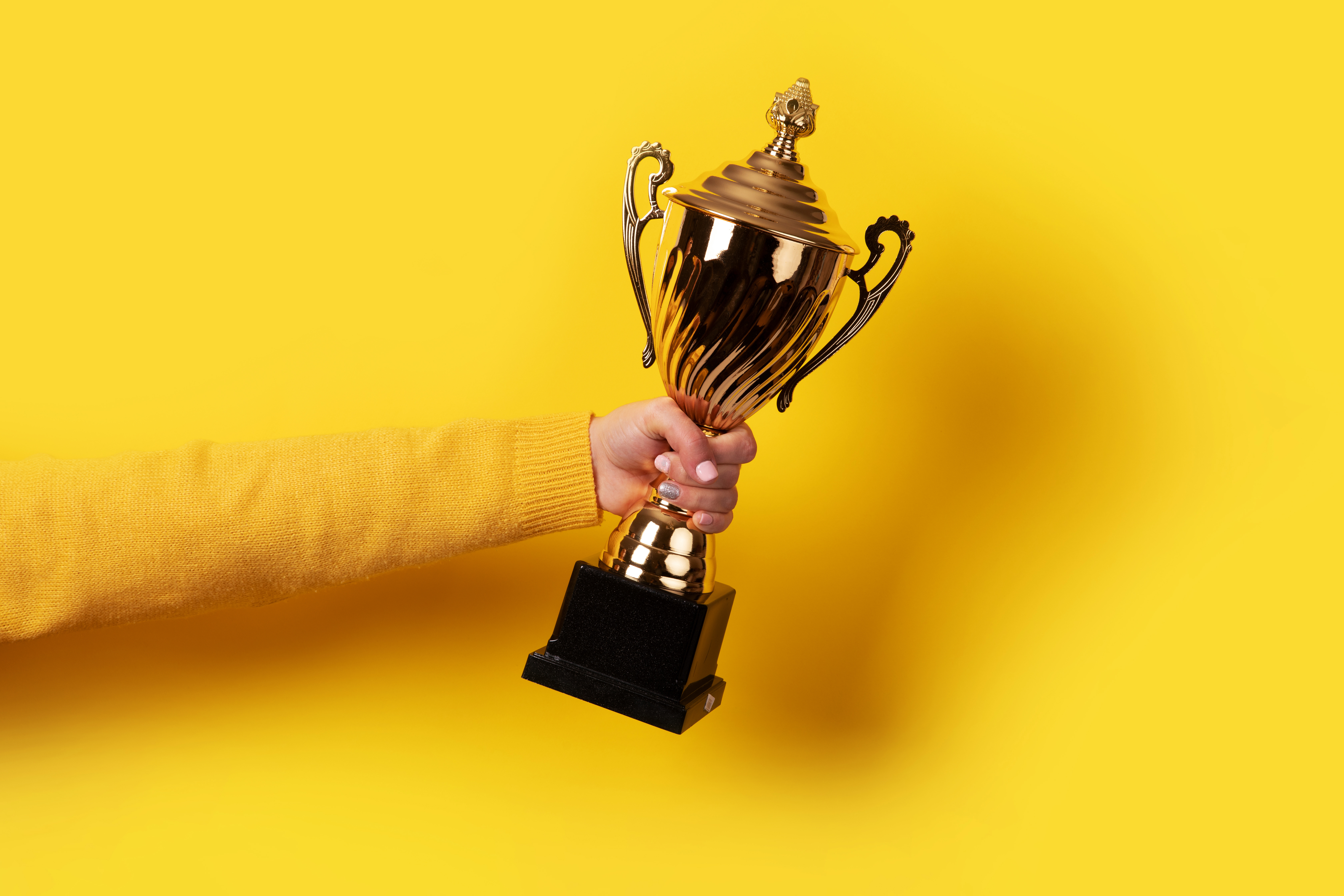 Woman holding a trophy against a yellow background