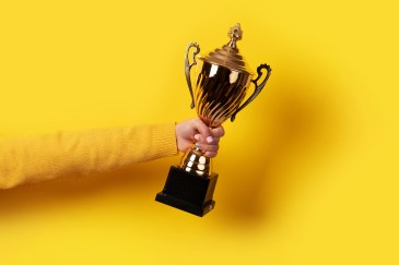Woman holding a trophy against a yellow background