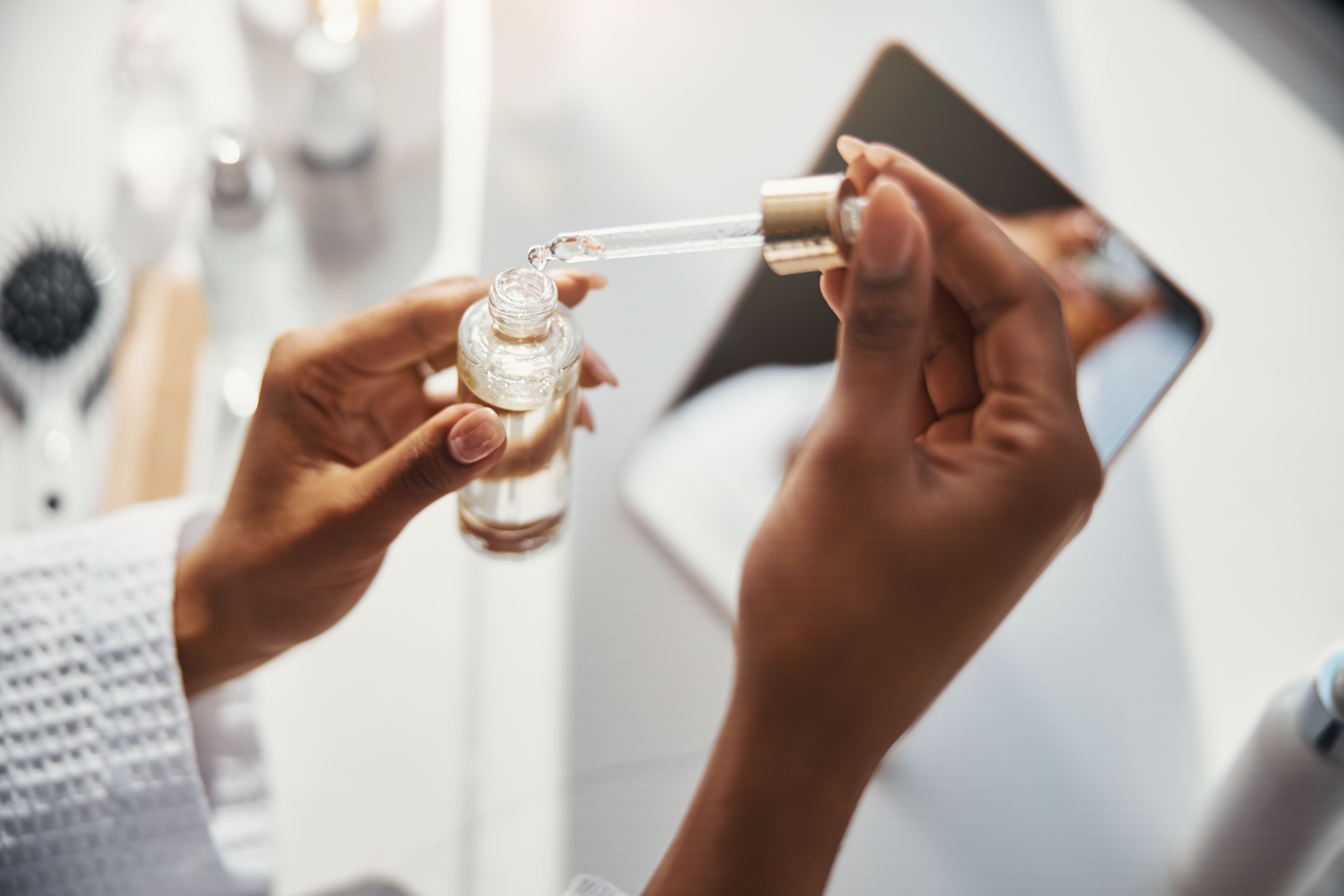 A black woman opens a bottle of skin vitamin serum.