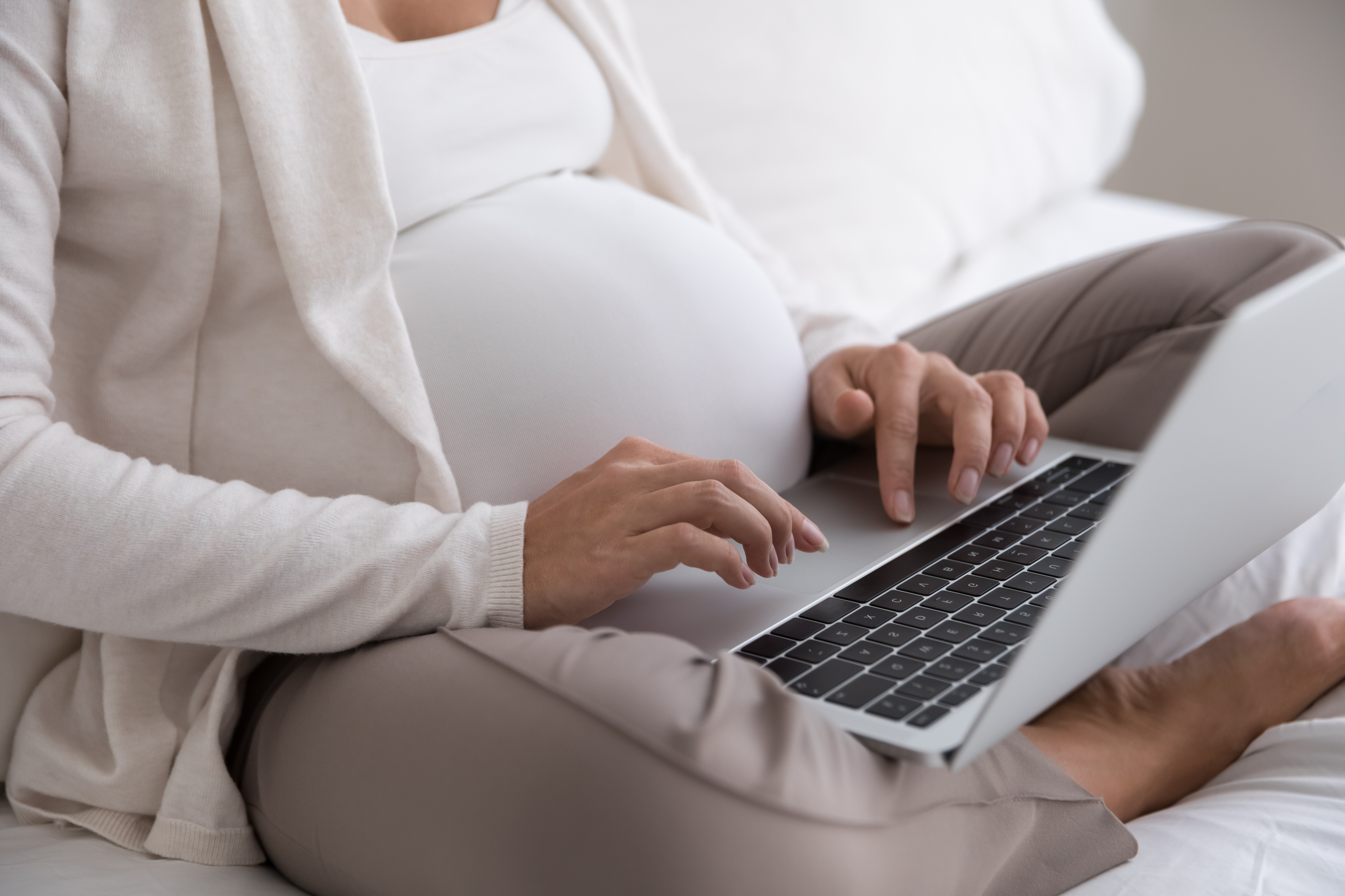 Pregnant woman typing on laptop