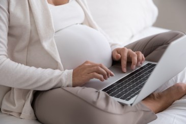 Pregnant woman typing on laptop
