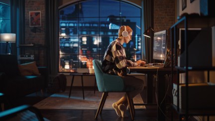 A young woman writing code in her city loft apartment in the early evening.