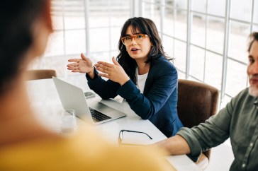 Woman in her 40s talking to coworkers in a meeting