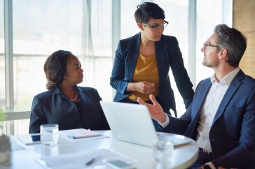 Managers in a work meeting sitting around a computer