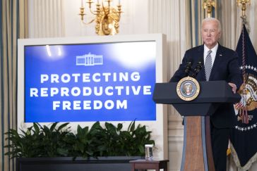 President Biden at press conference, next to a screen that reads "Protecting reproductive freedom."