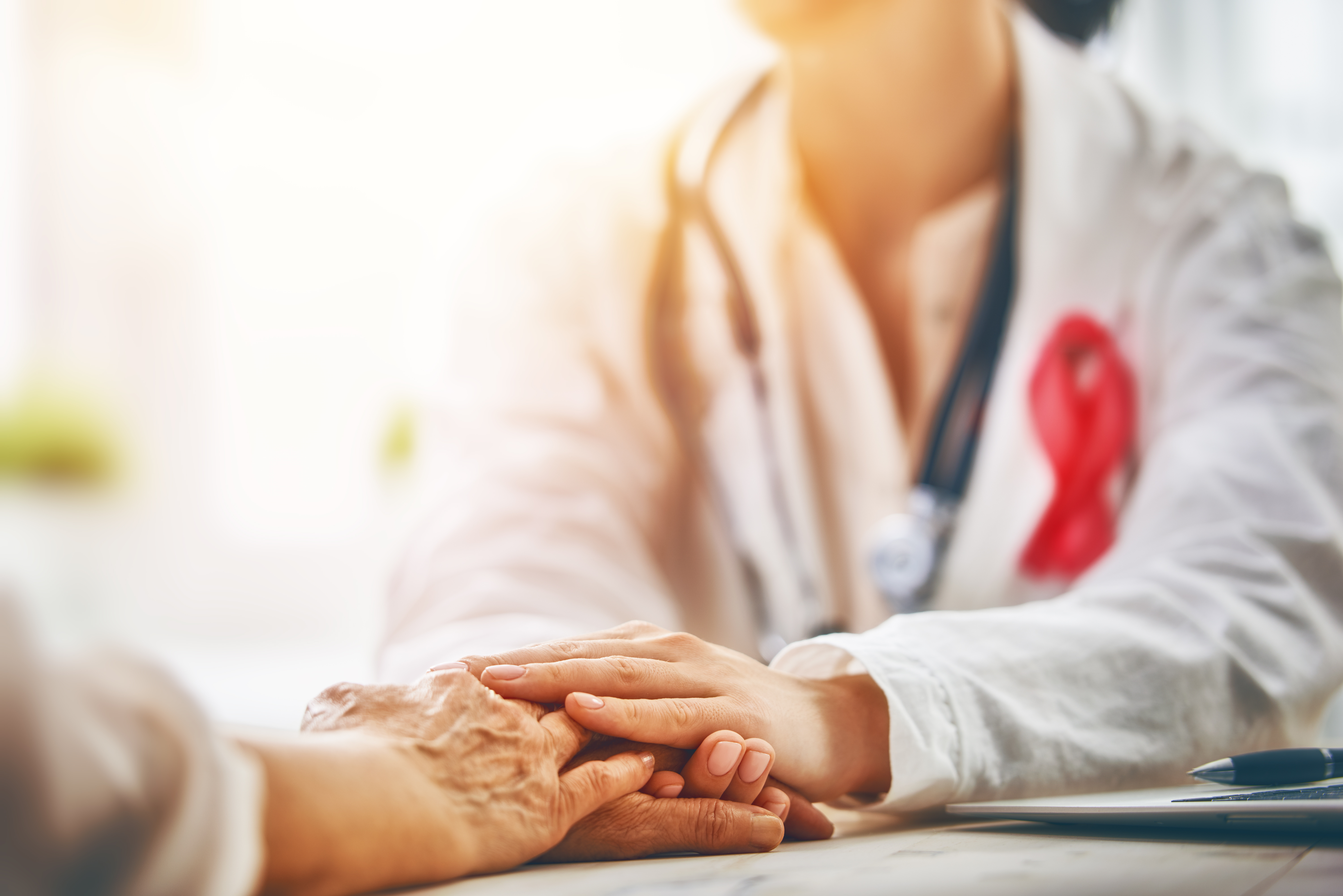 A doctor holds the hands of a patience, the focus is on the hands.