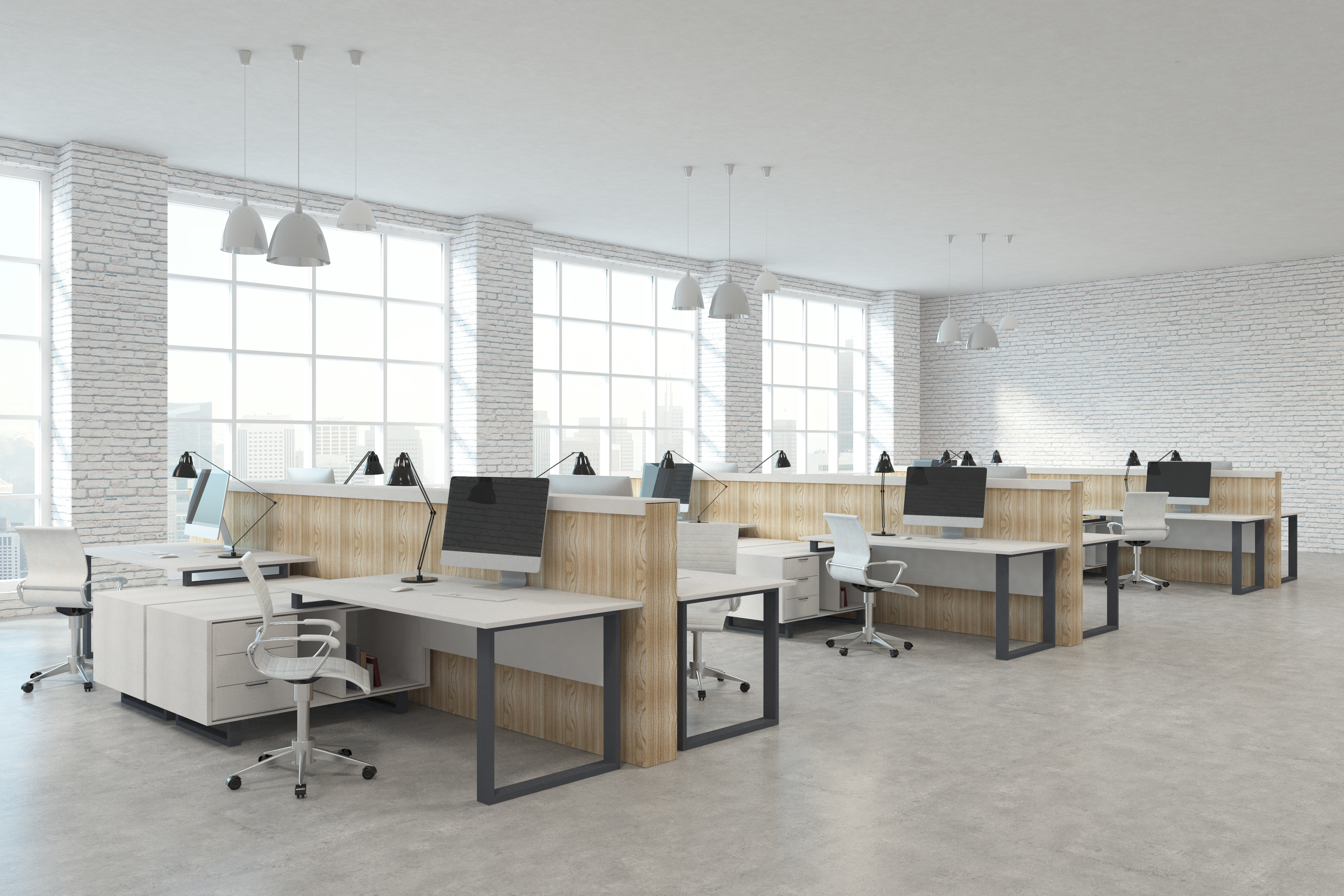A modern office space with three rows of white desks and Mac desktops.