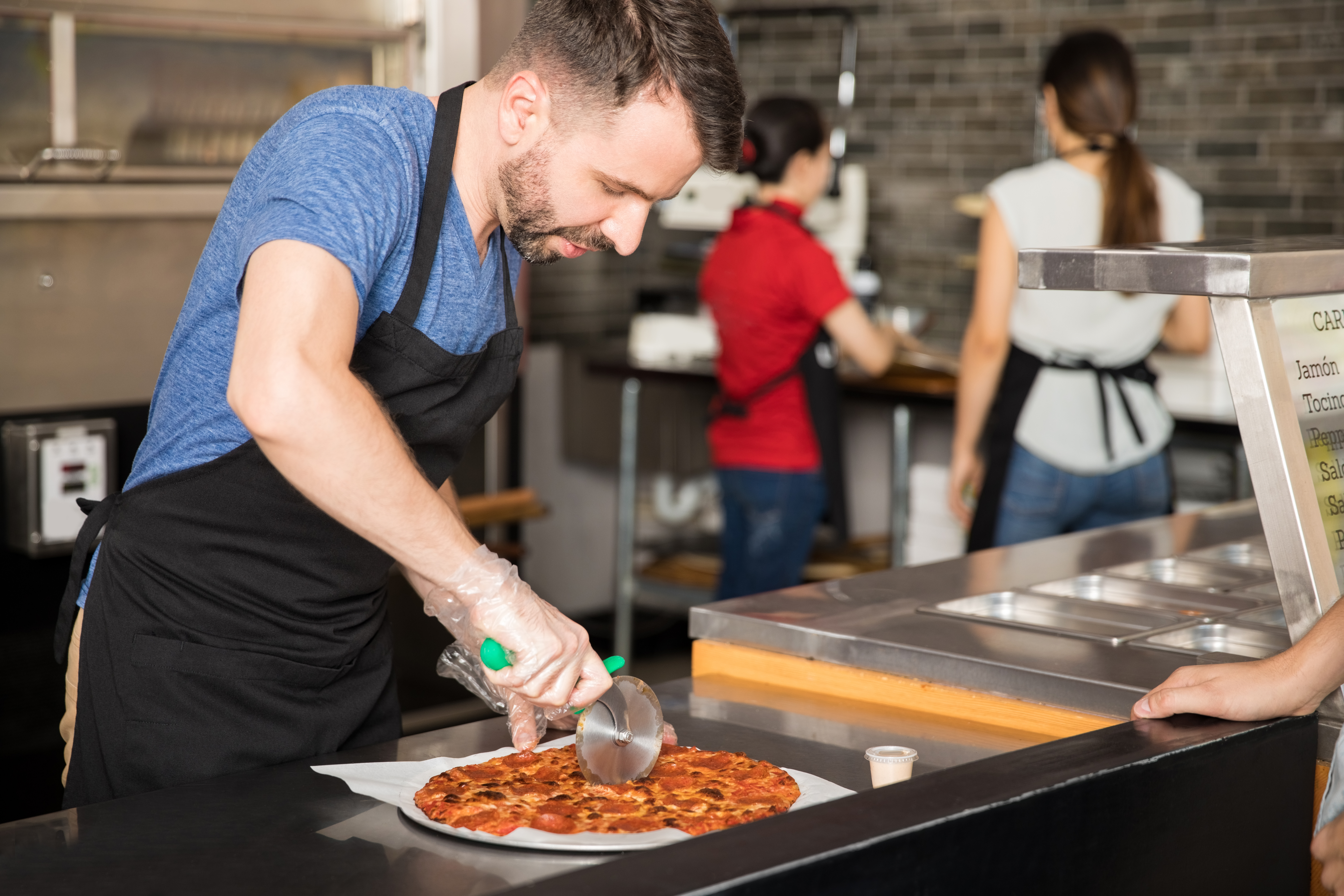 Employee cutting pizza in restaurant