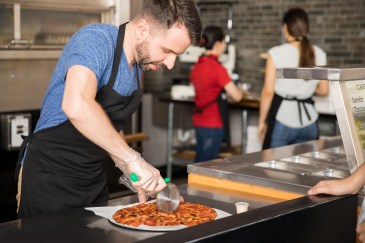 Employee cutting pizza in restaurant