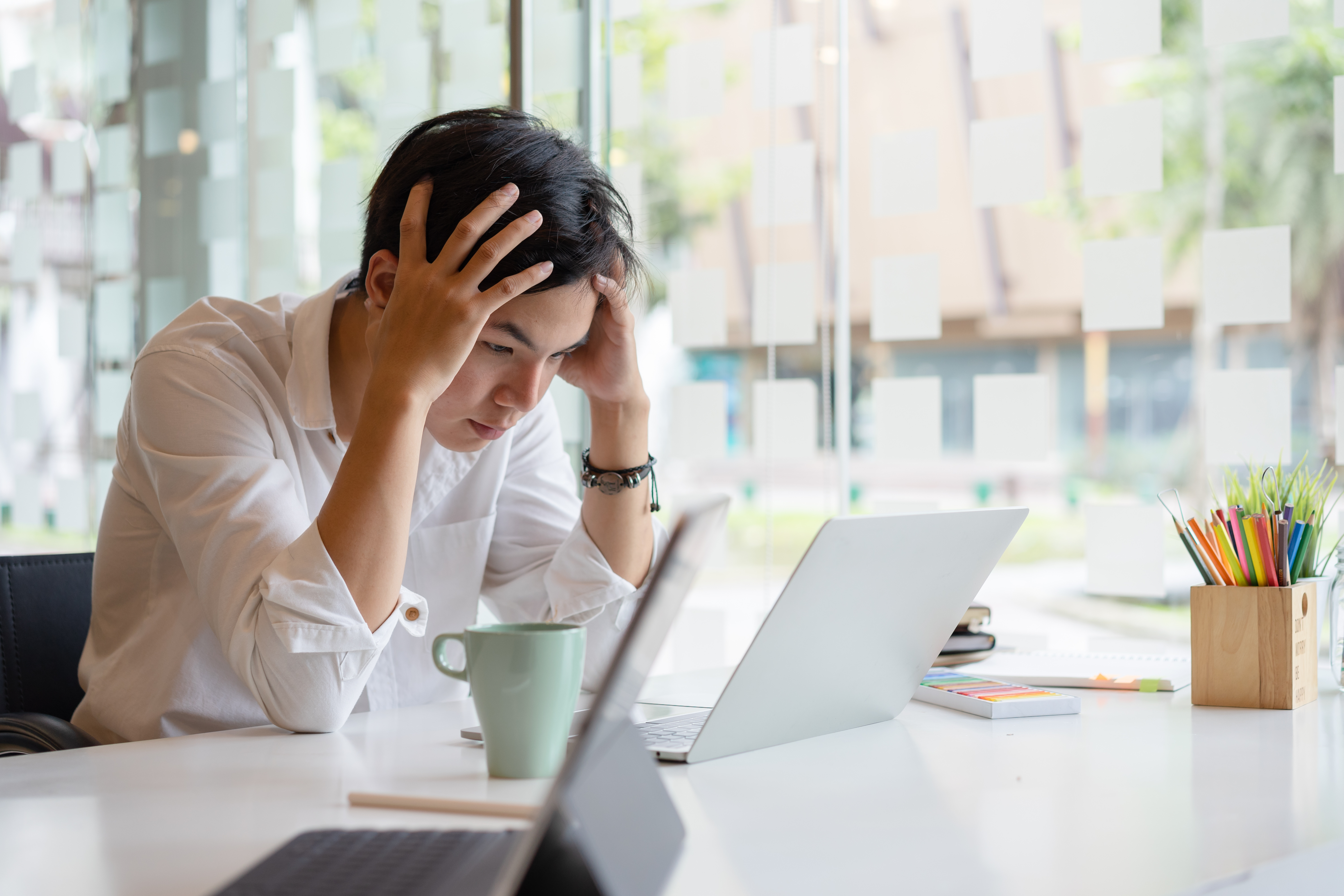 Man holding his head while looking at a computer