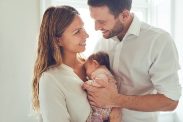 Couple smiling with newborn baby