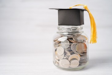 A jar of coins with a graduation cap on top