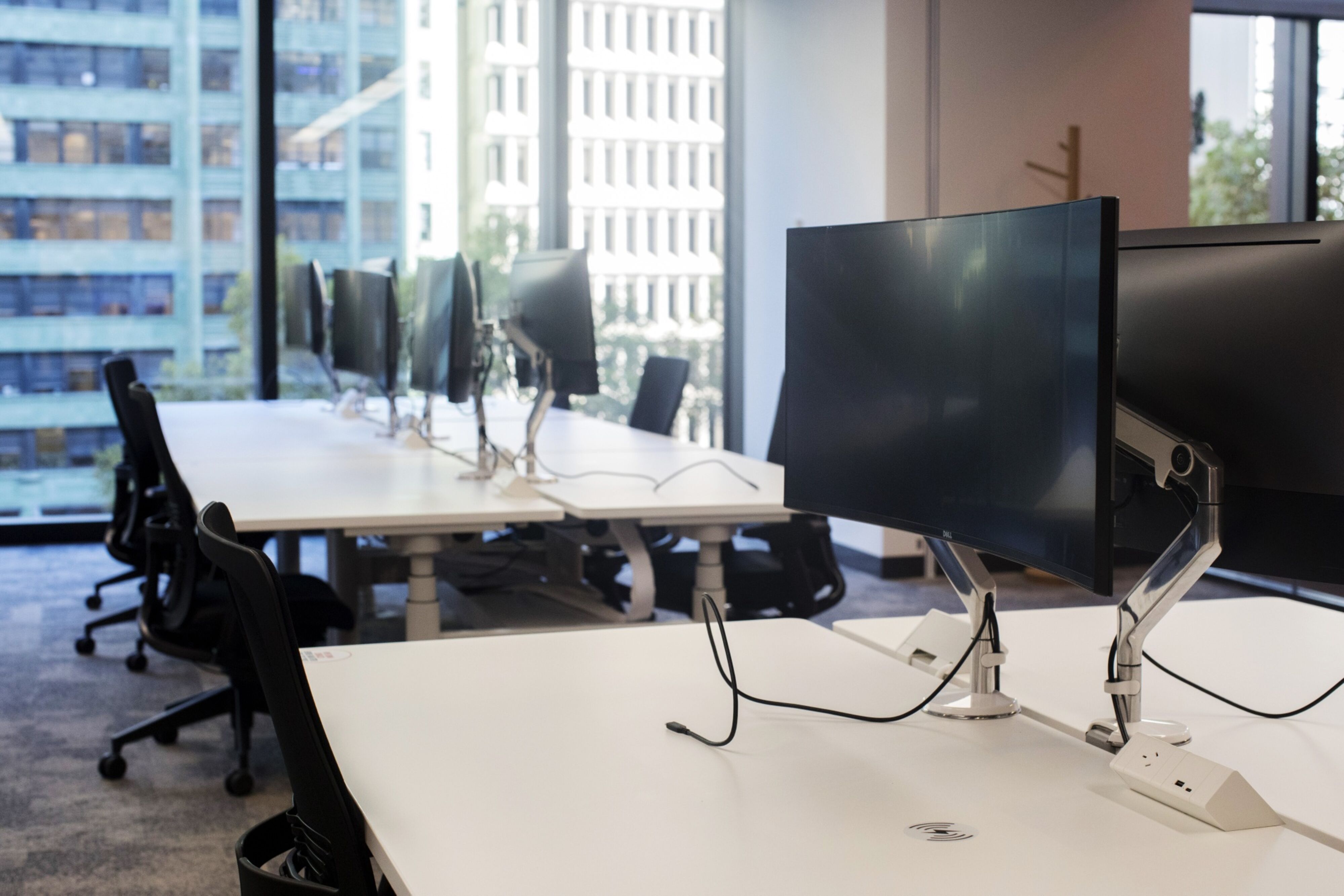 Inside of an office with an empty row of desks with unplugged computers