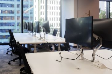 Inside of an office with an empty row of desks with unplugged computers