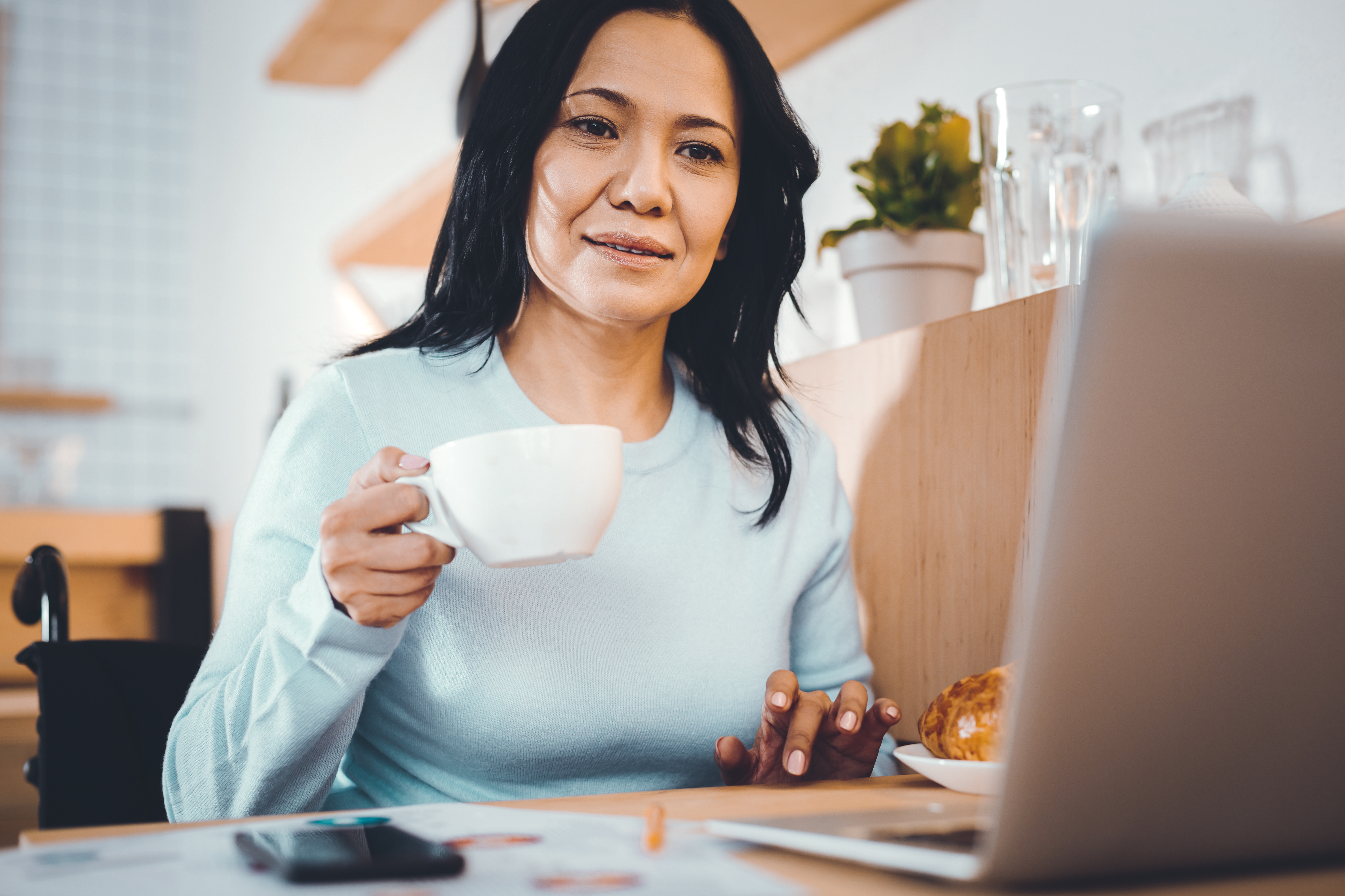 Woman looking at her computer while holding a cup of coffee