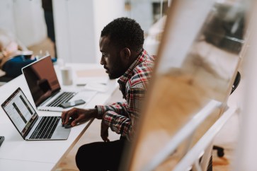 Young employee scrolls on his laptop in the office.