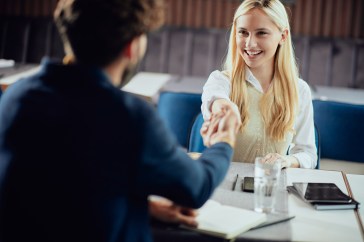 Young woman shaking an interviewers hand.