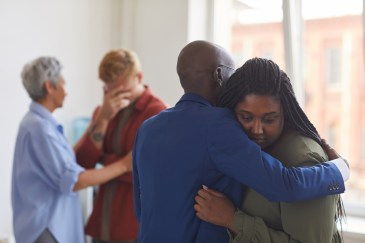 Man hugging a woman who looks upset, while another woman comforts a man in the background