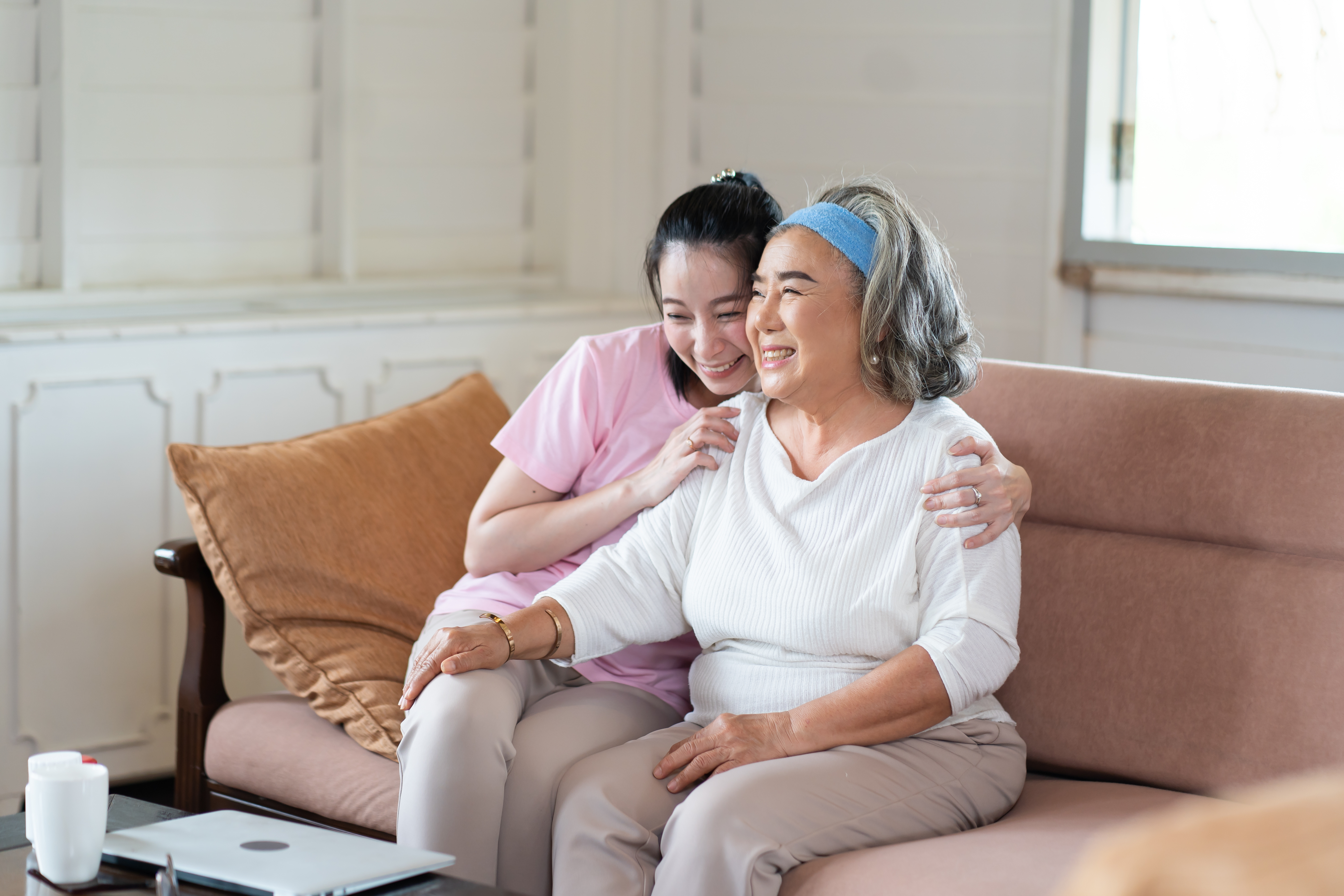 Adult woman hugging her mother on couch smiling