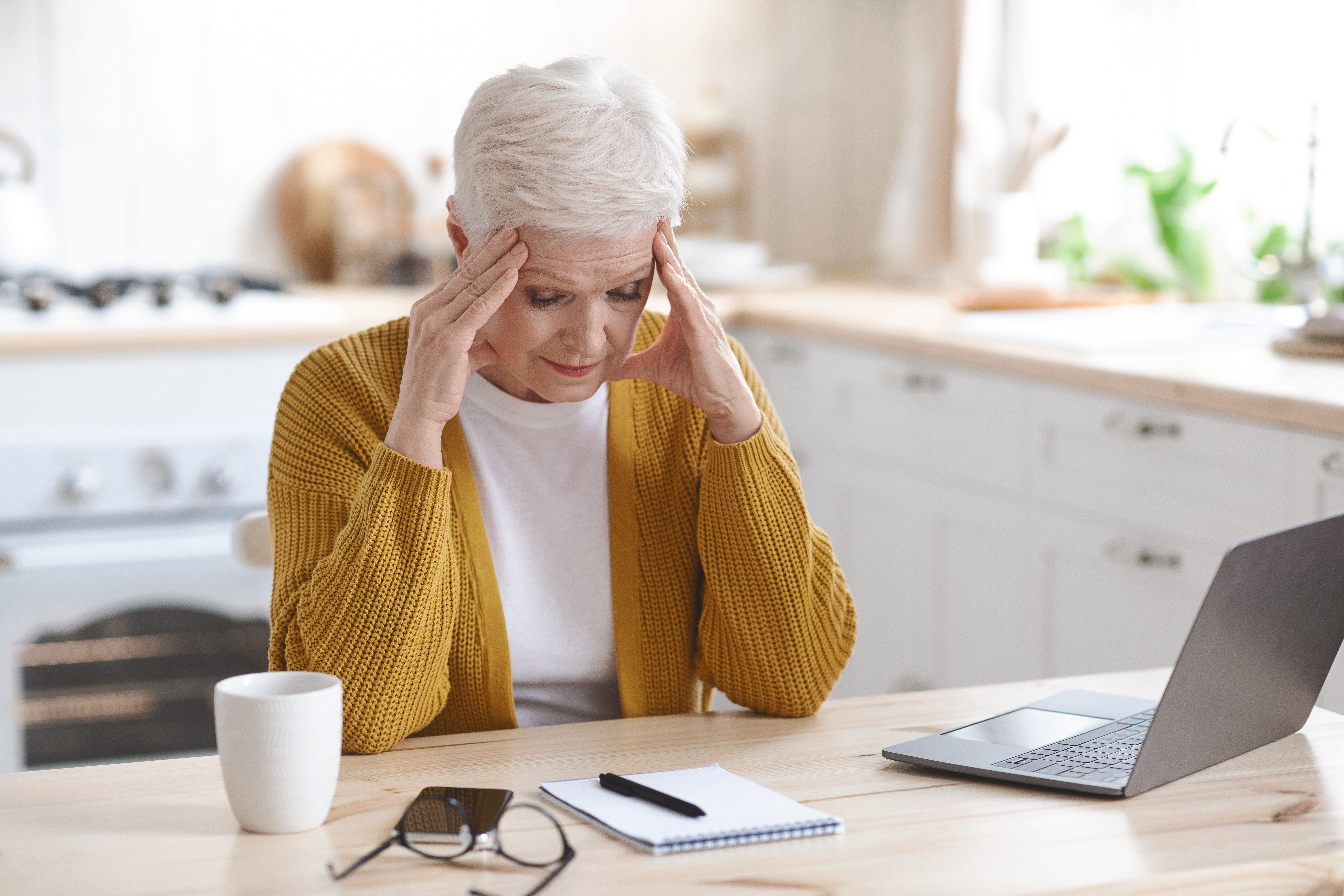 Older woman with her head in her hands looking at a sheet of paper