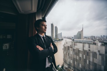 Man dressed in suit looking out of big window at city skyline