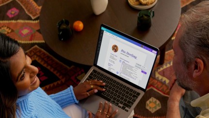 A south-asian woman is showing her resume she built on Canva on her laptop to an elderly man