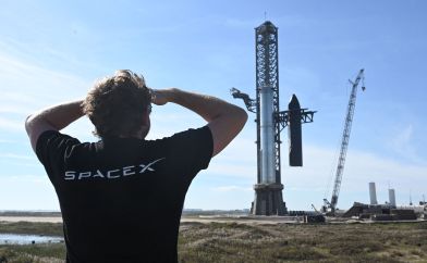 Man in a SpaceX t-shirt looking at a rocket launch