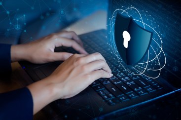 A laptop bathed in blue light with a key lock icon hovering over it.