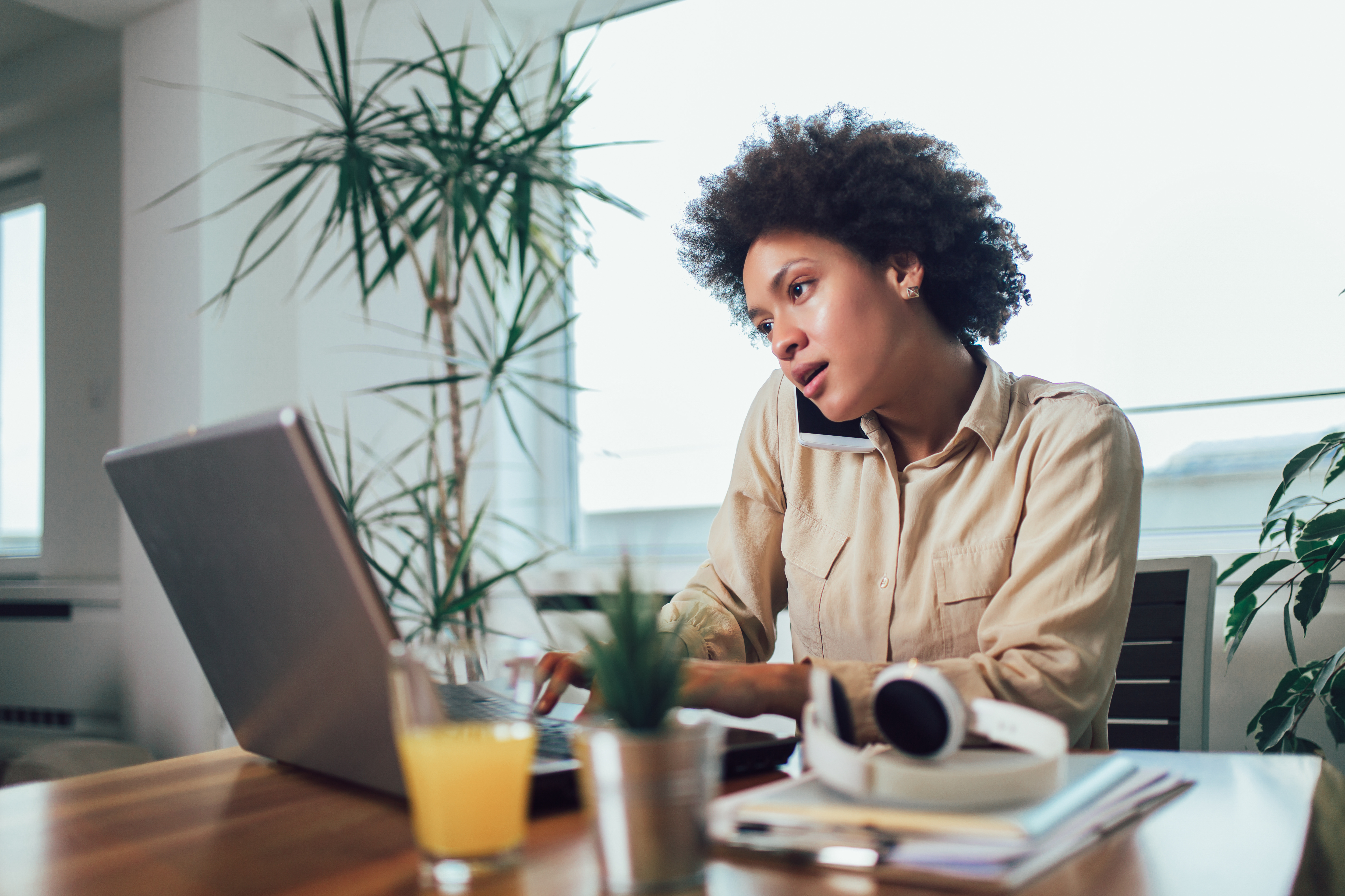 Woman on phone and working on computer at dining table